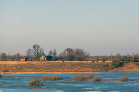 picturesque landscape of the river bed among brown forest with small houses on the horizon