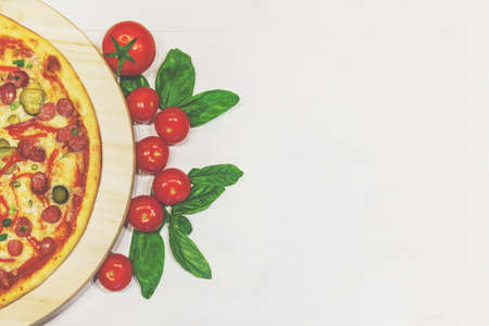 pizza with small sausages, basil and tomatoes on a white table, flat lay, retro toned, copy spaceの写真素材