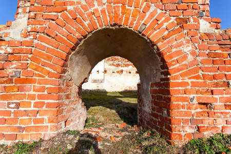 arched entrance to the wall on the ruins of an old medieval red brick buildingの写真素材