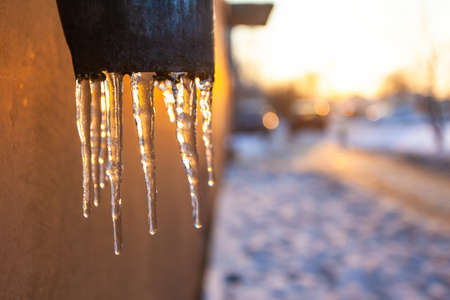 melting icicles on the drainpipe against the bright sunの写真素材