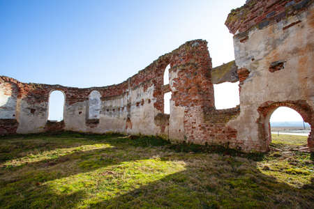 interior, ruined walls and courtyard, overgrown with grass in the ruins of an old medieval red brick buildingの写真素材