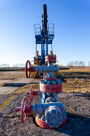 pipe and valve close up next to an aboveground oil producing tower