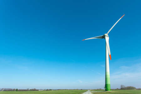 wind turbine among a green field against a blue sky, copy space