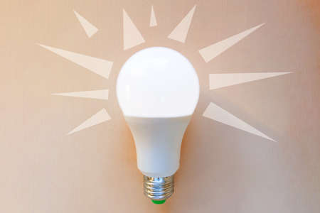 bright white LED lamp with painted rays on an orange background, concept ideas