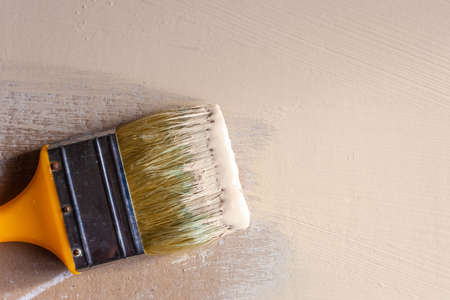 paint brush in beige paint on painted drywall, copy spaceの写真素材