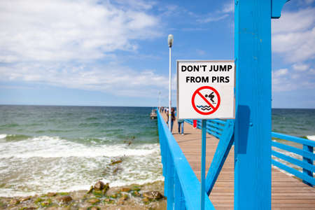 warning sign on the seashore at the pier with the words "DONT JUMP FROM PIRS"の写真素材
