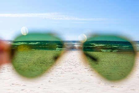 sea and beach on a sunny summer day through green sunglassesの写真素材