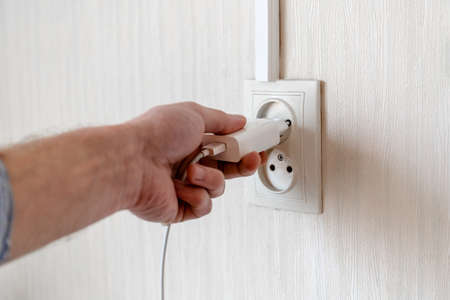 man's hand plugs into a power outletの写真素材
