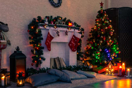 Christmas decorated fireplace with socks next to the Christmas tree, gifts, toys and garland lightsの写真素材