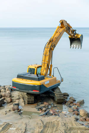 excavator on the beach, strengthening the beach and installing breakwaters