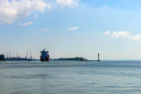 a large cargo ship comes into port on a sunny day