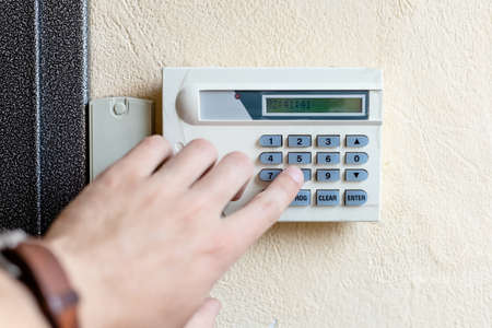 male hand turns on the alarm in the apartment