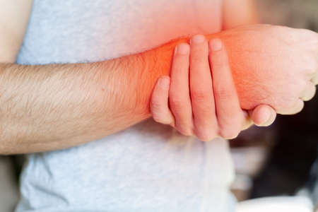 close up of a man's hands holds his wrist in pain