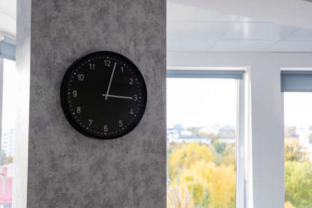 big black clock on the wall in a bright room