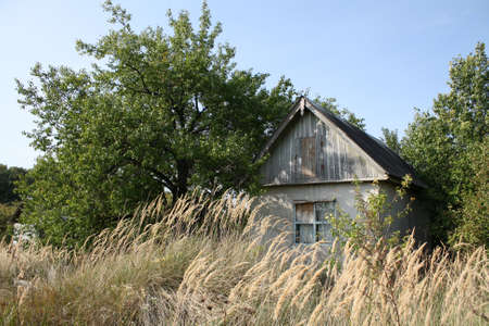 An abandoned old house in a field with boarded up windowsの写真素材