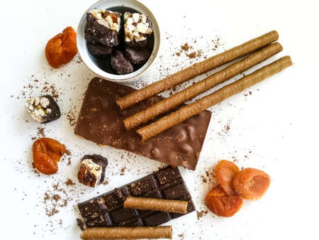 Different varieties of chocolate, chocolate tubes and cocoa on a white tableの写真素材
