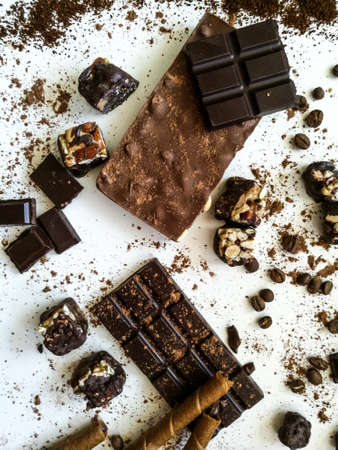 Different varieties of chocolate, chocolate tubes and cocoa on a white tableの写真素材