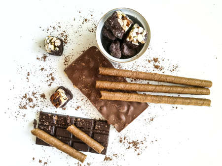 Different varieties of chocolate, chocolate tubes and cocoa on a white tableの写真素材