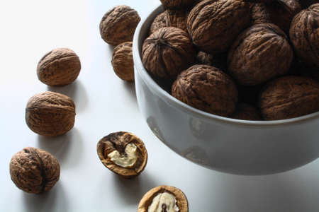 walnuts in a white bowl on a white table and a nutcrackerの写真素材