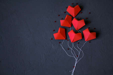 Origami red hearts made of paper on a dark blue background laid out in the form of balloons. Valentine day.の写真素材