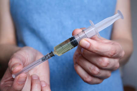 A young, pregnant woman holds a syringe in front of herの写真素材