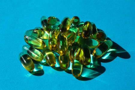 Fish oil capsules are scattered on the blue surfaceの写真素材