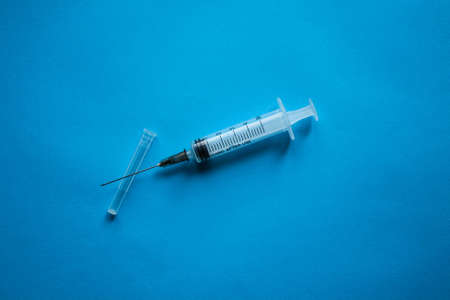 A syringe without a package filled with yellow medicine located on a blue background in the center of the composition.の写真素材