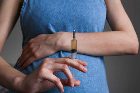 A young, pregnant woman holds a syringe in front of herの写真素材