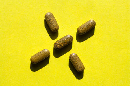 Tablets laid out in the form of a cross on a yellow backgroundの写真素材