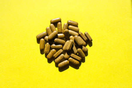 A pile of tablets scattered on the yellow surfaceの写真素材