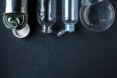 Recycling garbage is scattered on a dark surface.の写真素材