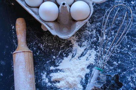 Baking utensils and ingredients are spread out on the dark surface.の写真素材