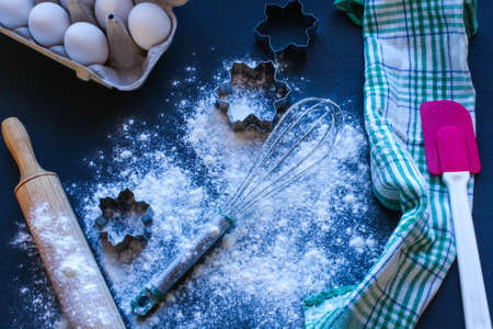 Baking utensils and ingredients are spread out on the dark surface.の写真素材