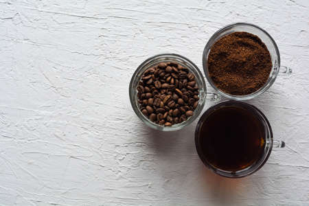 Three cups of ground coffee, coffee beans and brewed coffee in one rowの写真素材