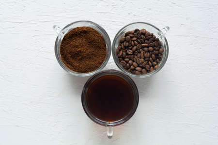 Three cups of ground coffee, coffee beans and brewed coffee in one rowの写真素材