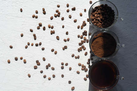 Three cups of ground coffee, coffee beans and brewed coffee in one rowの写真素材