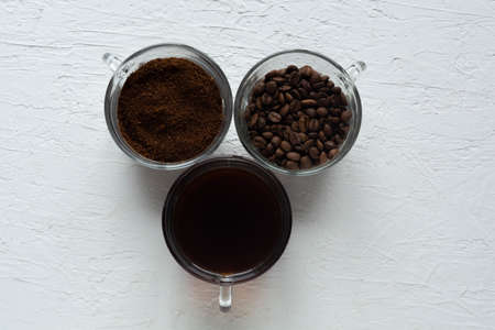 Three cups of ground coffee, coffee beans and brewed coffee in one rowの写真素材