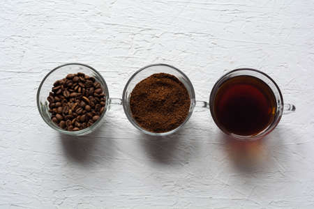 Three cups of ground coffee, coffee beans and brewed coffee in one rowの写真素材