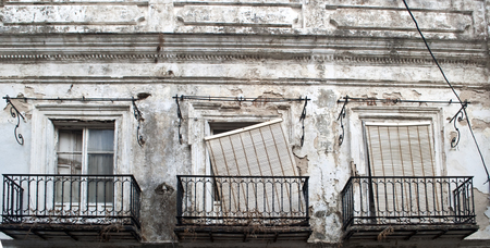 Three windows with balconies and shutters, in ruins