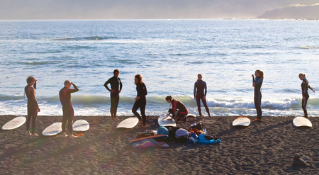 Several men and women on the beach getting surfing lessons