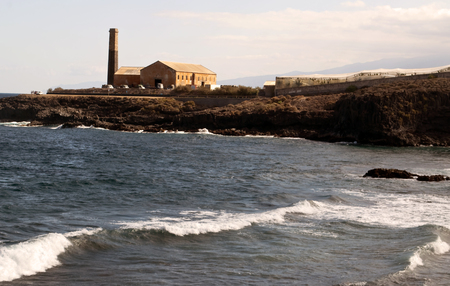 View of a factory from the rocky beach of the caleta on the Spanish island of Tenerifeの写真素材
