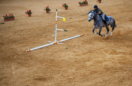 rider in uniform on horseback with a spear trying to puncture a balloonのeditorial素材