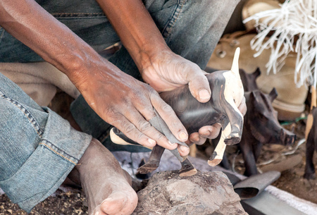 ARUSHA, TANZANIA - MAY 2014. Local Tanzanian men carving wood on the ground at Mto wa Mbu village, Arusha Regionのeditorial素材