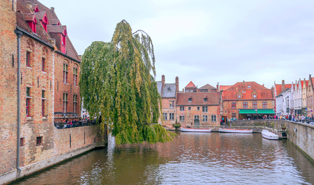 BRUGES, FLANDERS, BELGIUM-SEPTEMBER 2014. Streets of Bruges in Belgium with its medieval style facades on a cloudy day. You see people walking through them.のeditorial素材