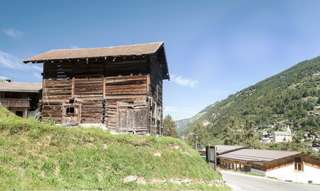 Wooden houses in the meadows of the Swiss Alps in the Saint Luc valley on a sunny day.の販売画像