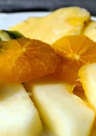 Apples and cut oranges served on a plateの写真素材
