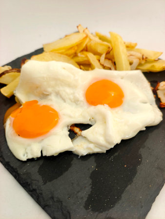 Fried eggs with potatoes served on a plateの写真素材