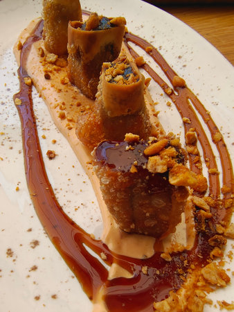 Crispy rolls with chocolate and caramel sauce on a white plate