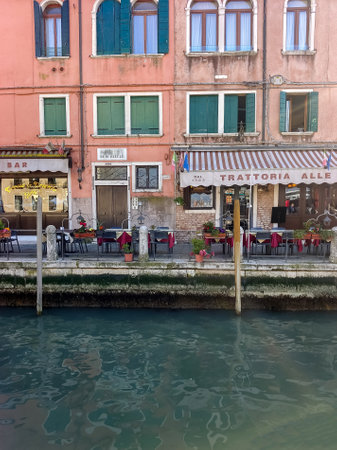 Venice, Italy - April 2023. Venice canals with boats sailing and tourists walking through its streets on a sunny dayのeditorial素材