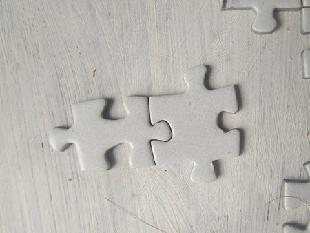 Piece missing from black jigsaw puzzle on white wooden background.の写真素材